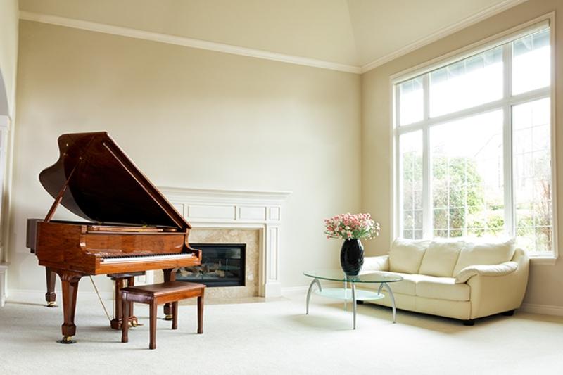 A clean living room with light beige carpet and walls with a fireplace and grand piano displaying good indoor air quality.